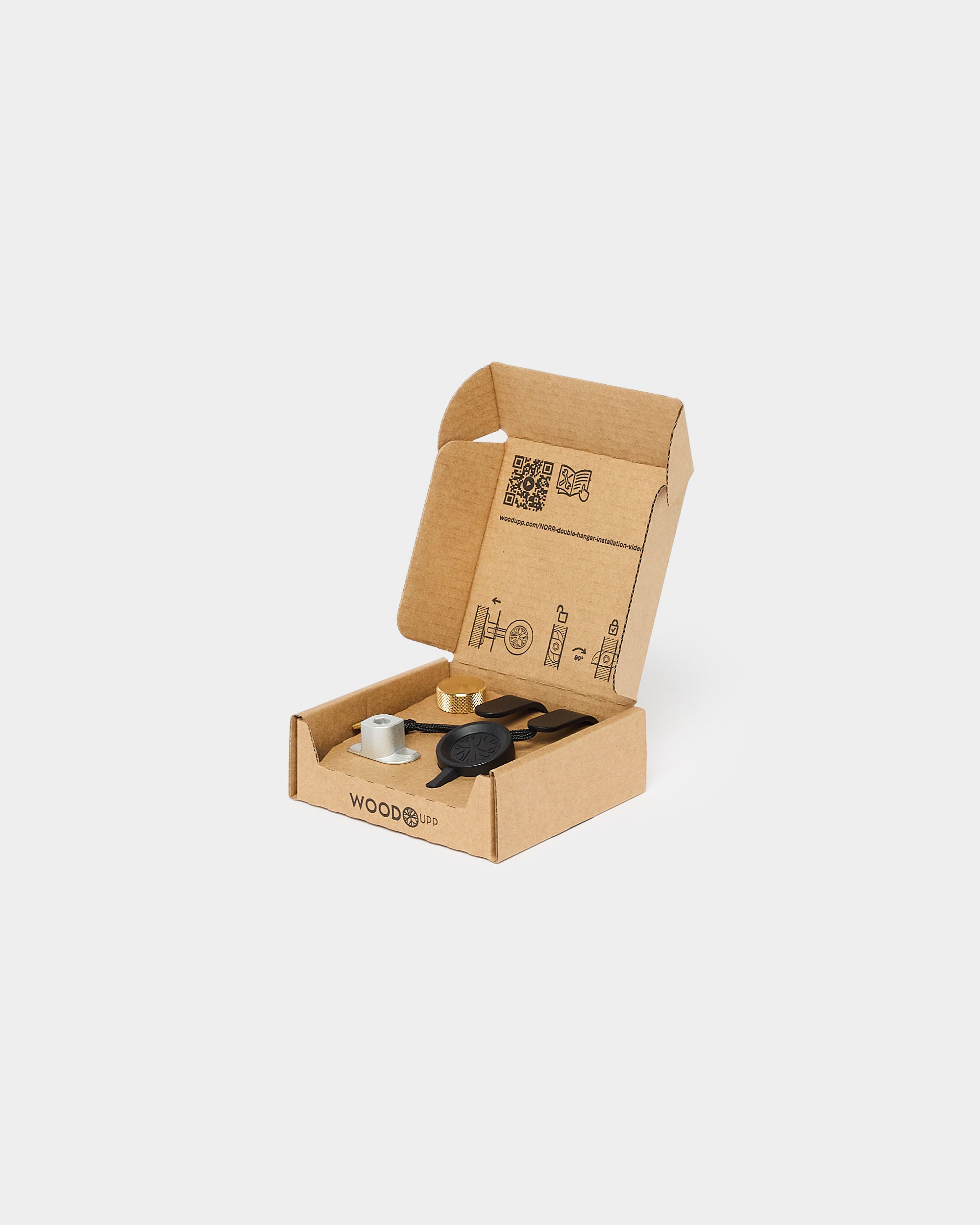 An open cardboard box containing small metal and rubber components for assembling or installing acoustic panels, placed on a plain white background.